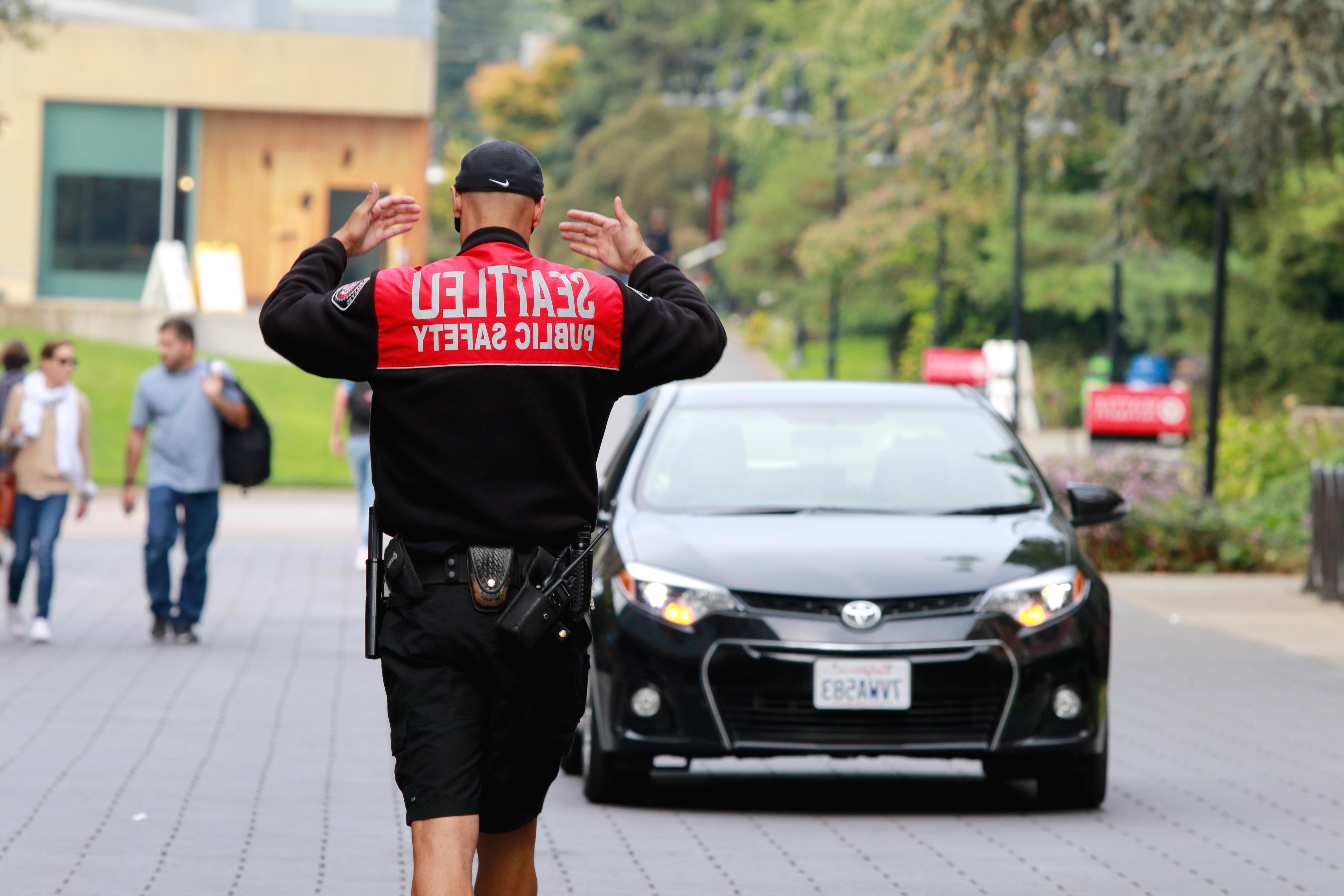 警察在指挥交通，双手高举. 后置摄像头. 一辆黑色轿车正向警官驶来.